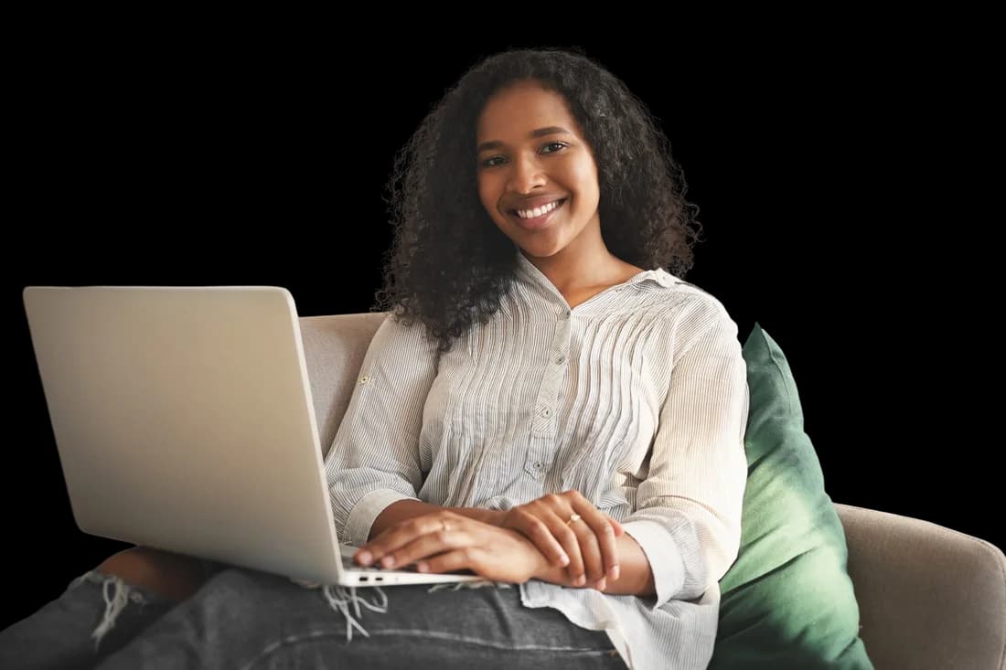 Mulher jovem sorridente usando um notebook em casa, navegando na internet.